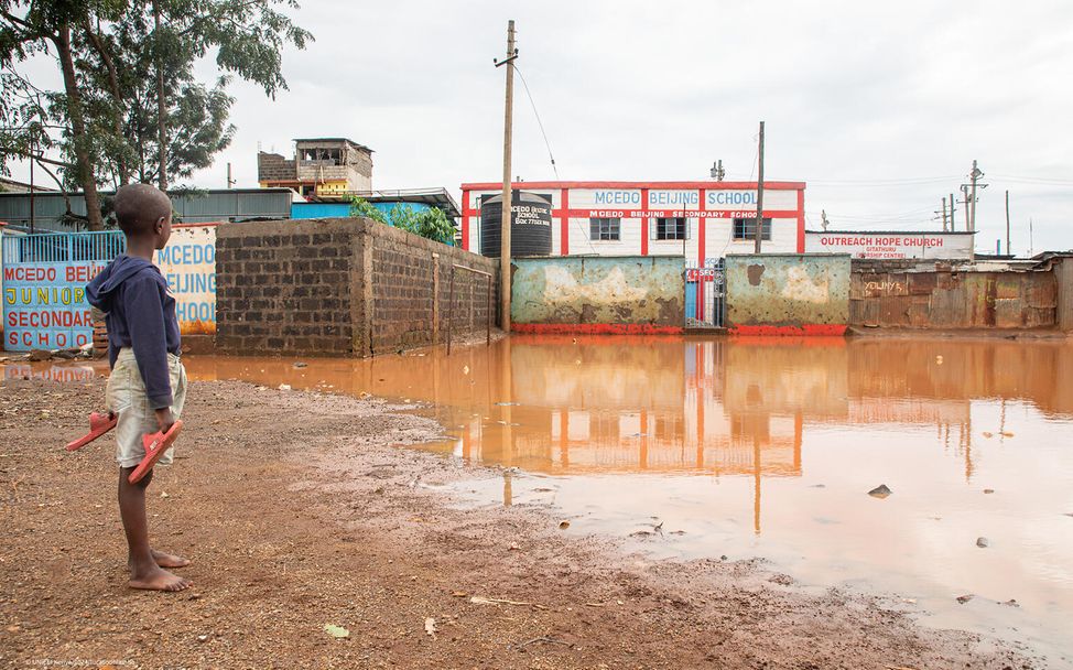 Ein kleiner Junge blickt auf seine Schule, die in Mathare, Nairobi, Kenia, von den Fluten überschwemmt wurde.