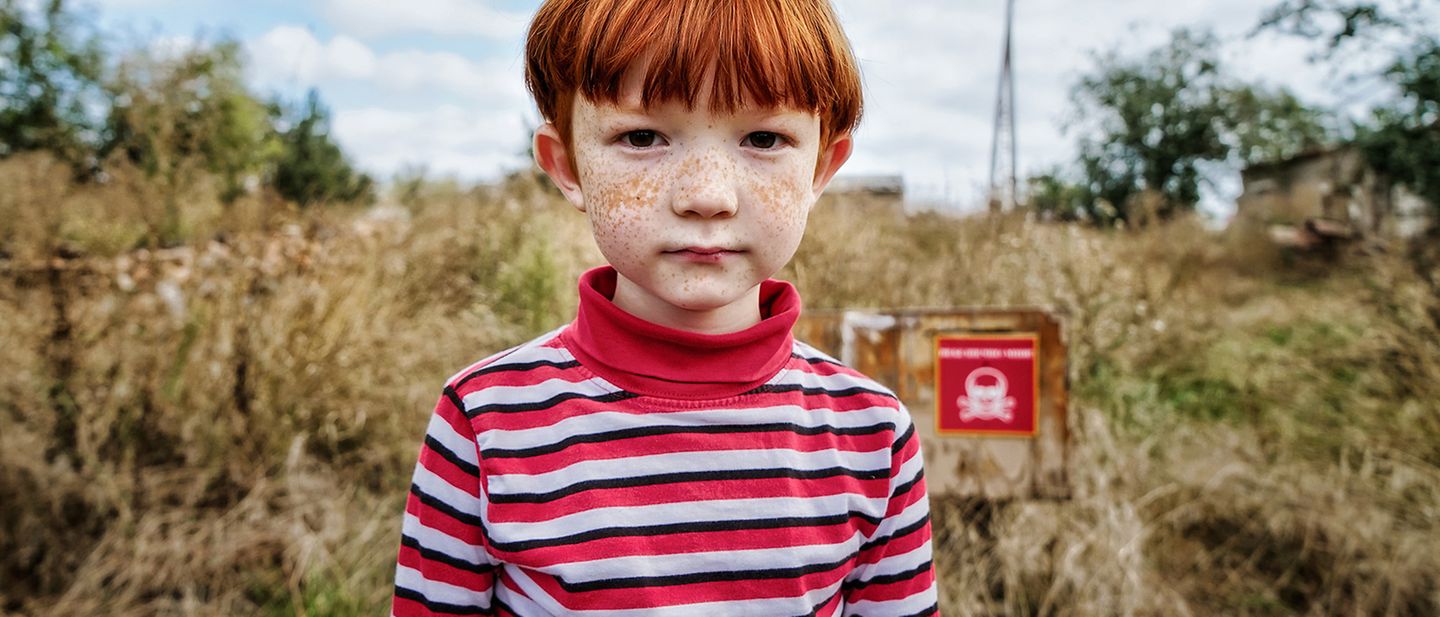 Krieg in der Ukraine: Junge steht vor einem Minenfeld nicht weit von seinem Zuhause. | © UNICEF/Hrom
