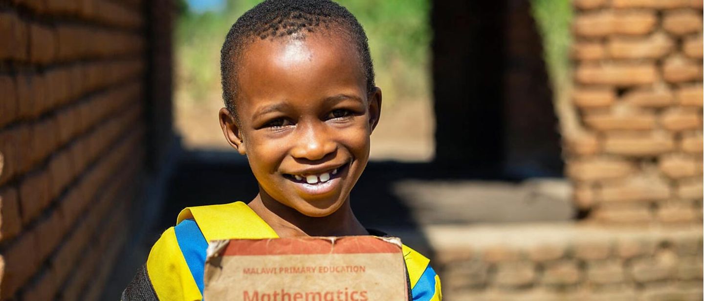 UNICEF in Malawi: Eine Erstklässlerin hält stolz ein Schulheft in der Hand 
