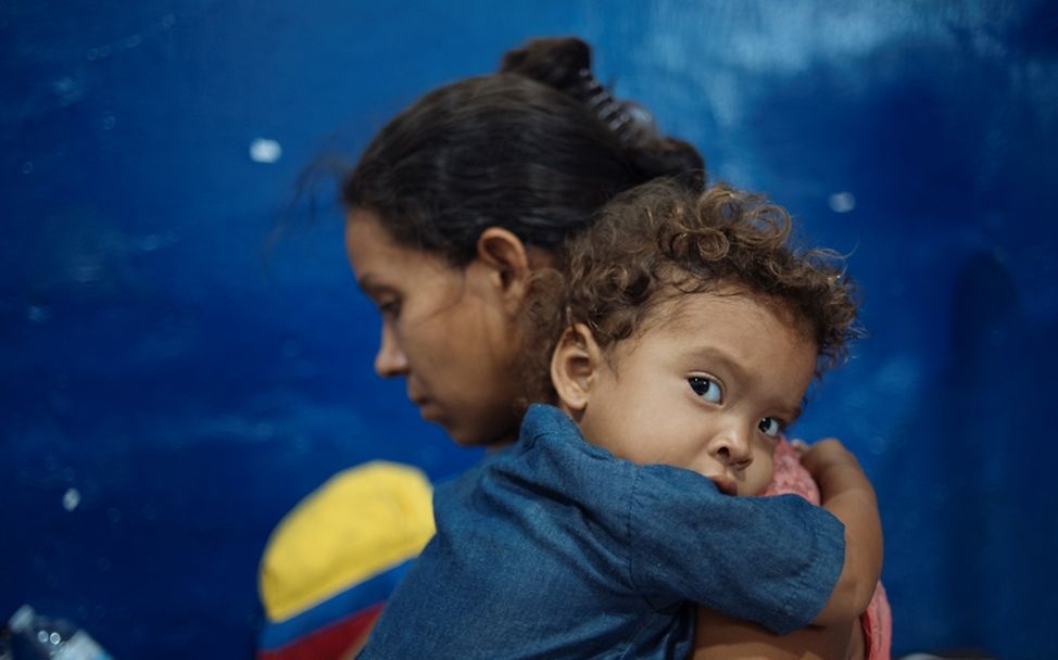 Weltflüchtlingstag: Maikel hält ihre Mutter Leidy Characo in der Raststätte in Kolumbien, wo sie ihre Reise zu Fuß fortsetzen