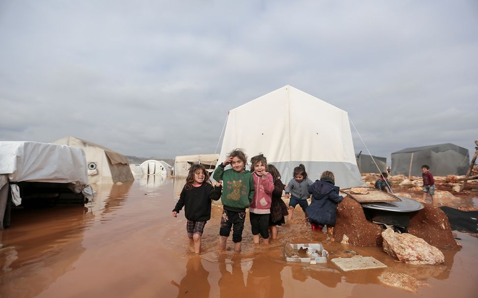 Weltflüchtlingstag: Kinder stehen in einem überfluteten Gebiet des Lagers Kafr Losin im Nordwesten von Syrien. 