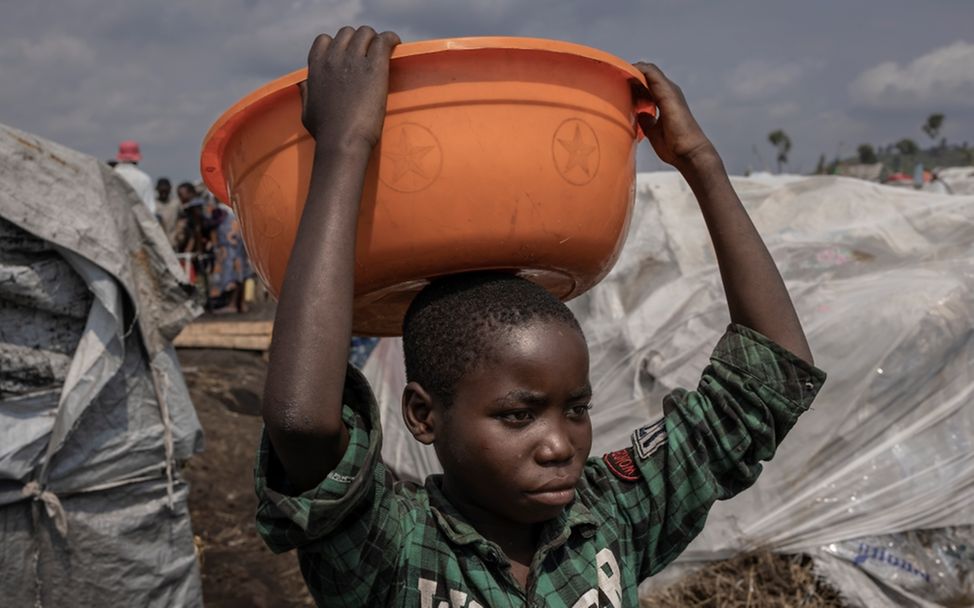 Weltflüchtlingstag: Merci Shivima, 12, trägt eine Schüssel mit Wasser im Flüchtlingslager Bulengo in der DR Kongo (Februar 2023)