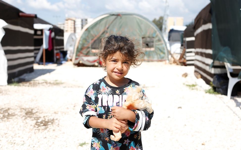 Weltflüchtlingstag: Ein Mädchen hält sein Spielzeug in einer Notunterkunft in Hatay, Türkei, nach zwei verheerenden Erdbeben.
