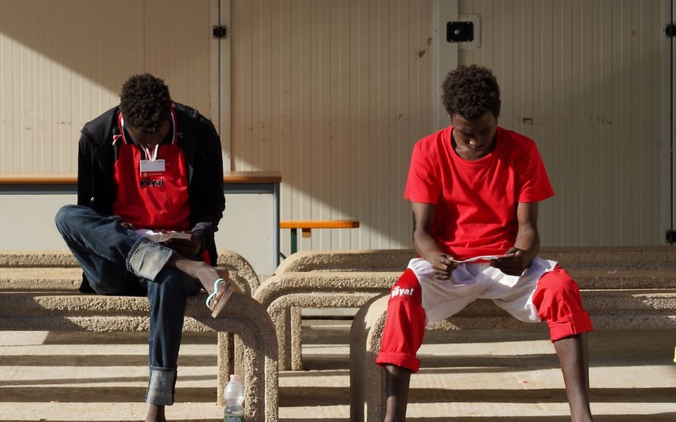 Weltflüchtlingstag: Jugendliche Migranten lesen im Aufnahmezentrum der Insel Lampedusa, Italien, Informationsbroschüren.